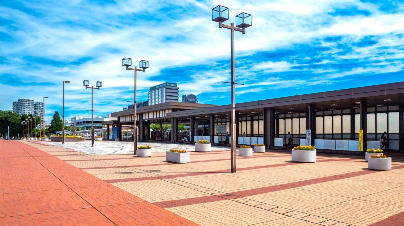 北総線千葉ニュータウン中央駅の駅舎と、花のプランターが並ぶ駅前広場(2022年撮影)