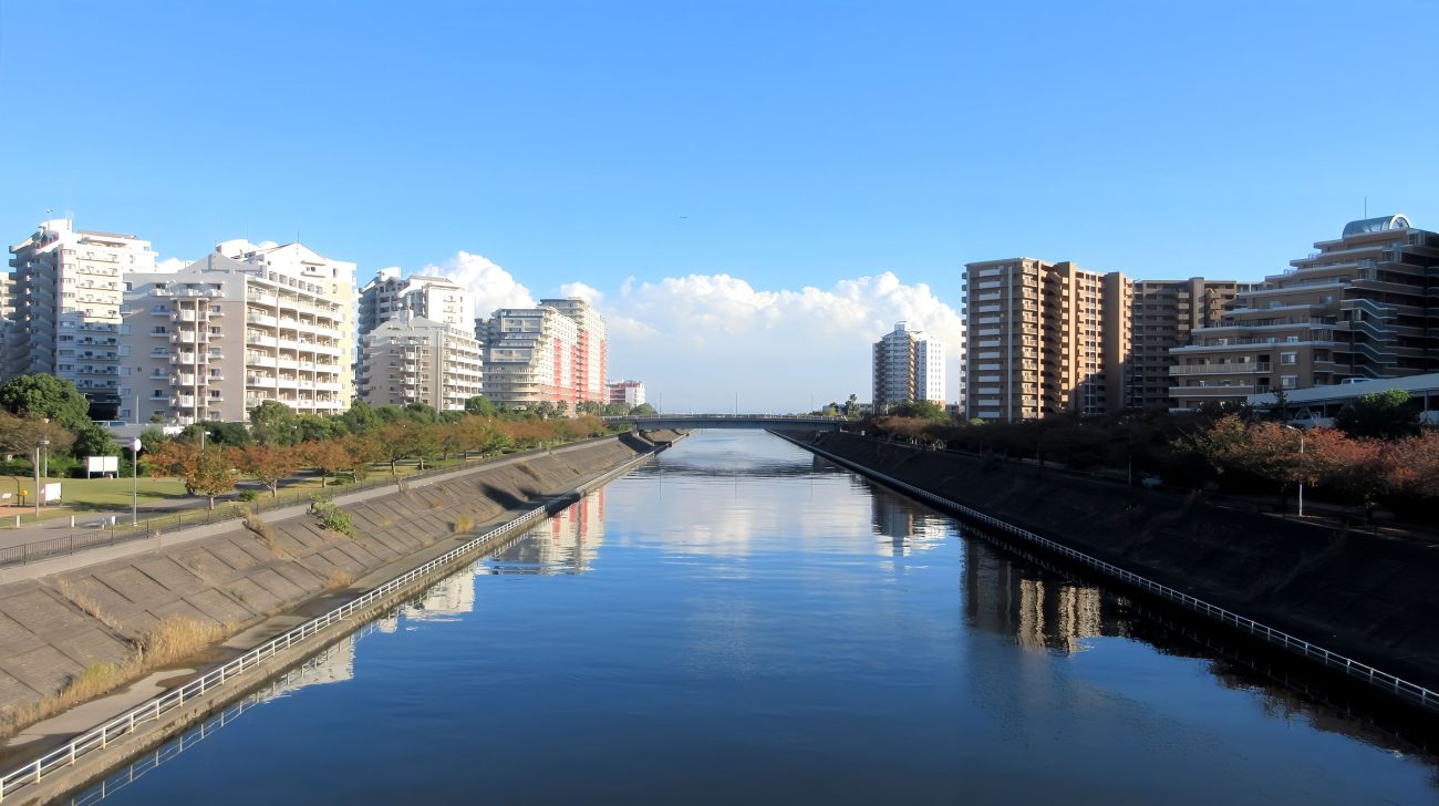 境川の水面と両岸に並ぶ住宅、青空(千葉県浦安市、2024年撮影)