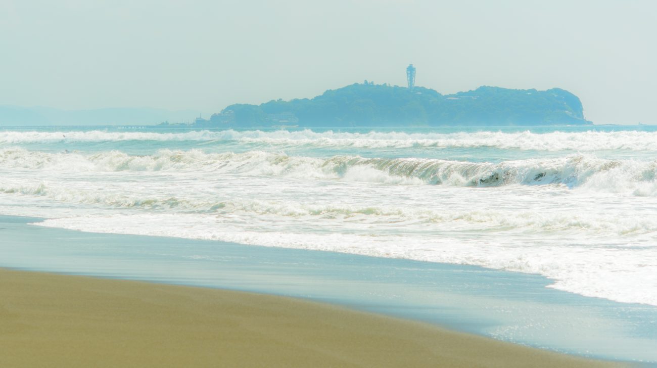 辻堂の砂浜に打ち寄せる波と、沖に見える江の島(神奈川県藤沢市、2015年撮影)