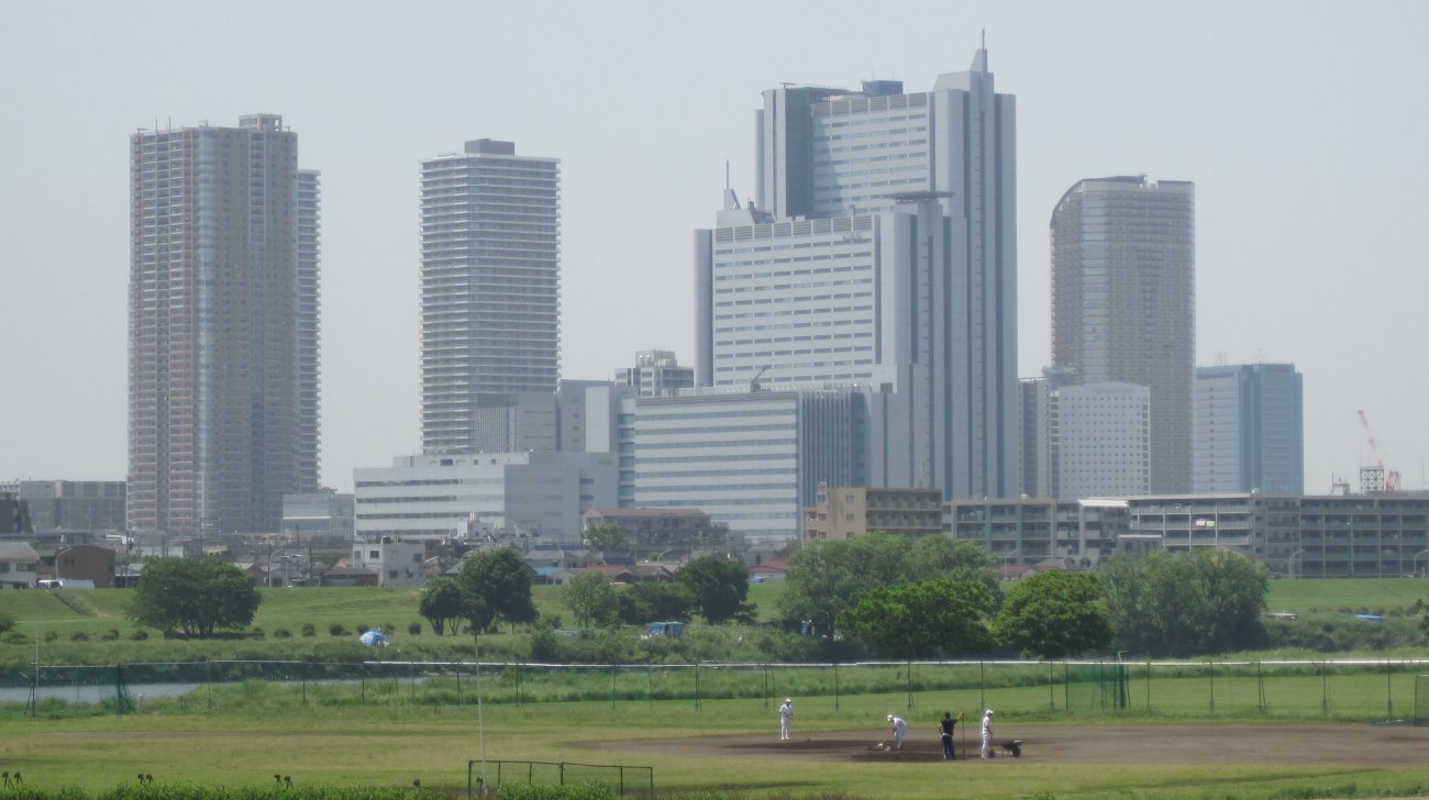 多摩川の河川敷のグラウンドと、その奥に並ぶ武蔵小杉の高層ビル群（2010年撮影）