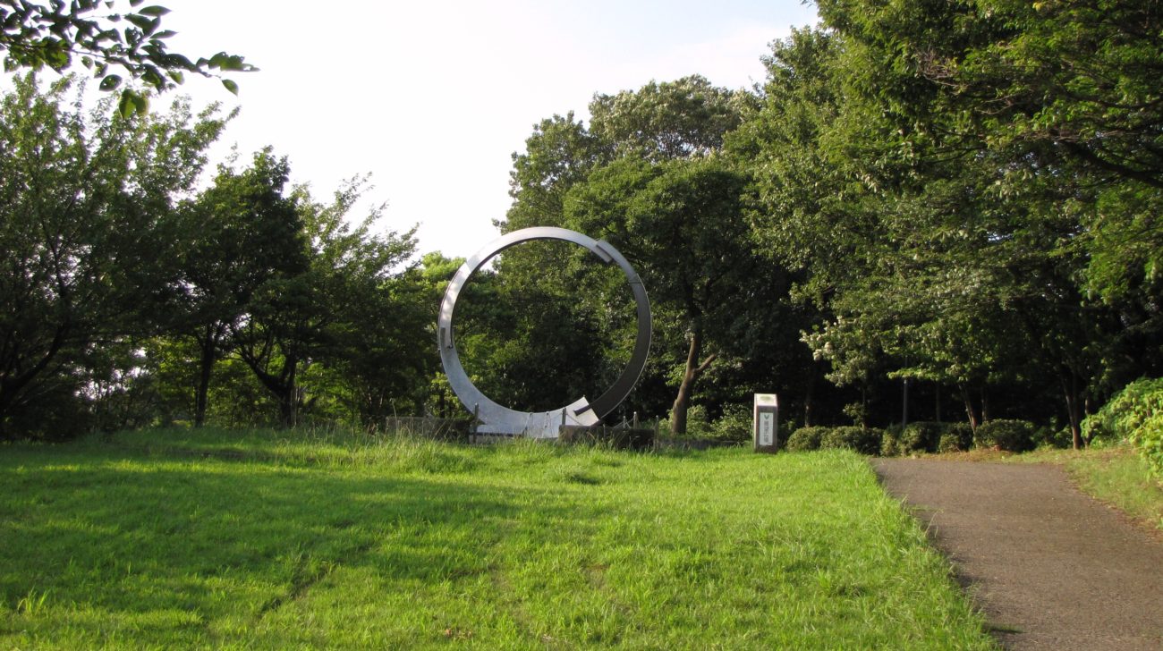 都筑中央公園（横浜市都筑区）の芝生広場と木立、輪の形のモニュメント（2011年撮影）