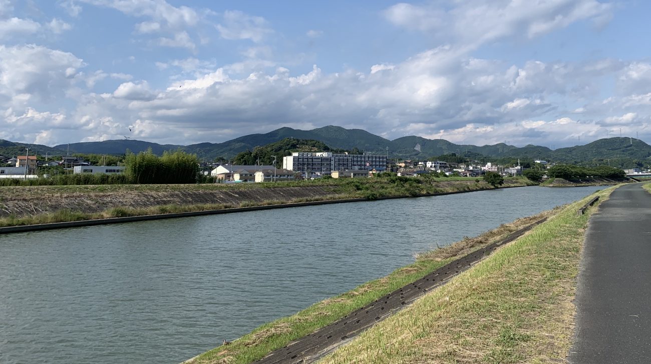 川沿いの道と山並み(浜松市浜名区、2022年)