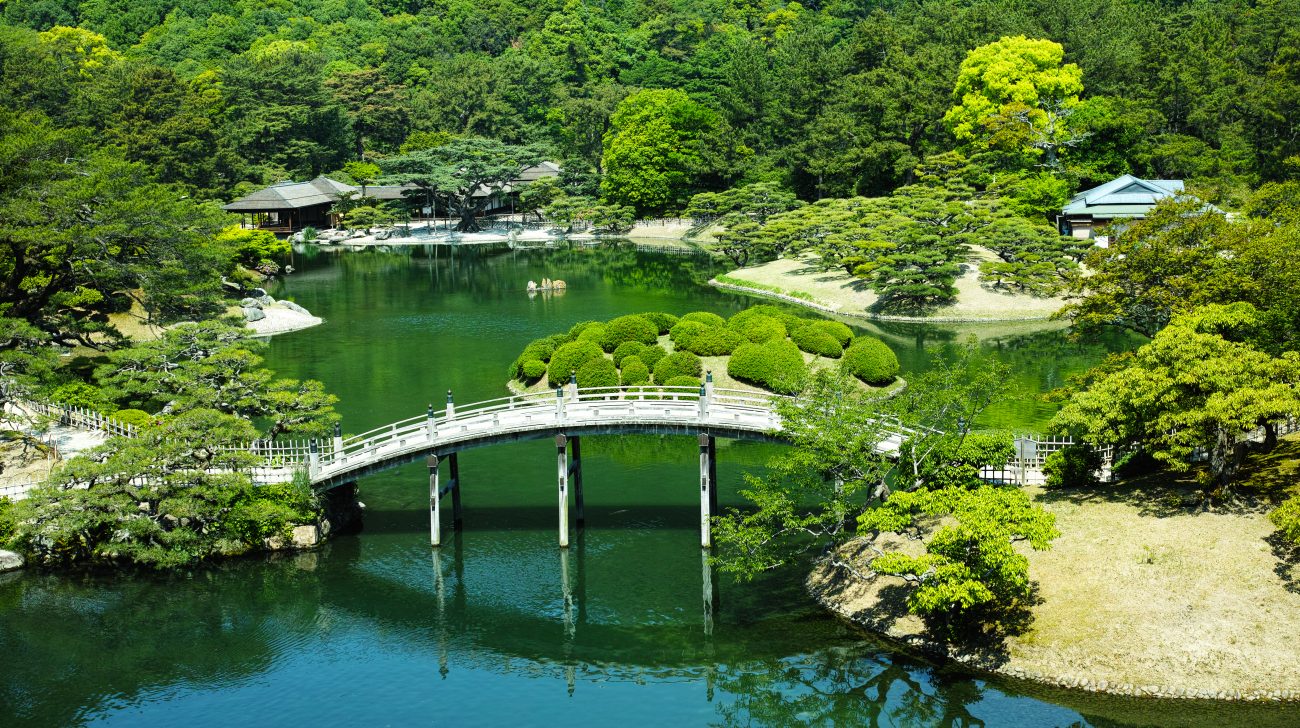 池と橋のある庭園と新緑の山(香川県高松市、2014年撮影)